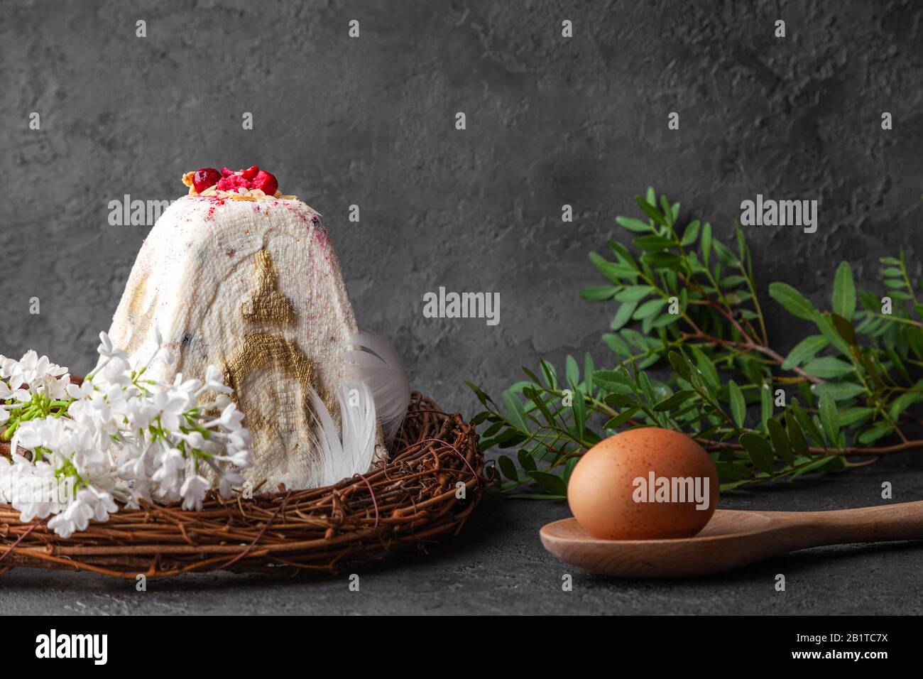 Fromage blanc cottage gâteau de pâques au kulich dans la tradition orthodoxe, oeuf sur cuillère en bois, fleurs blanches, bougies noires, couronne sur fond sombre, horizonta Banque D'Images