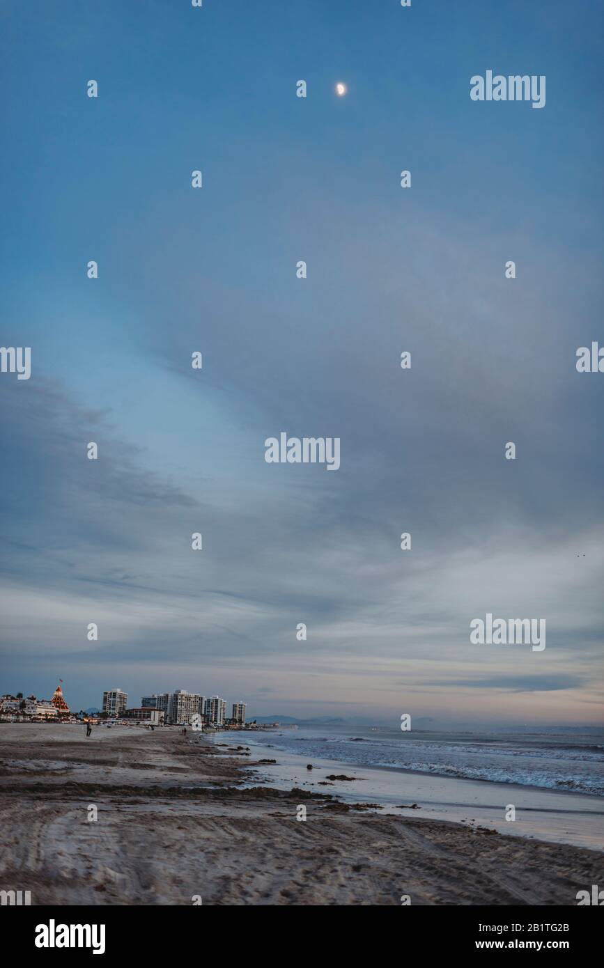 Paysage de plage au crépuscule avec lune et ciel bleu nuageux Banque D'Images