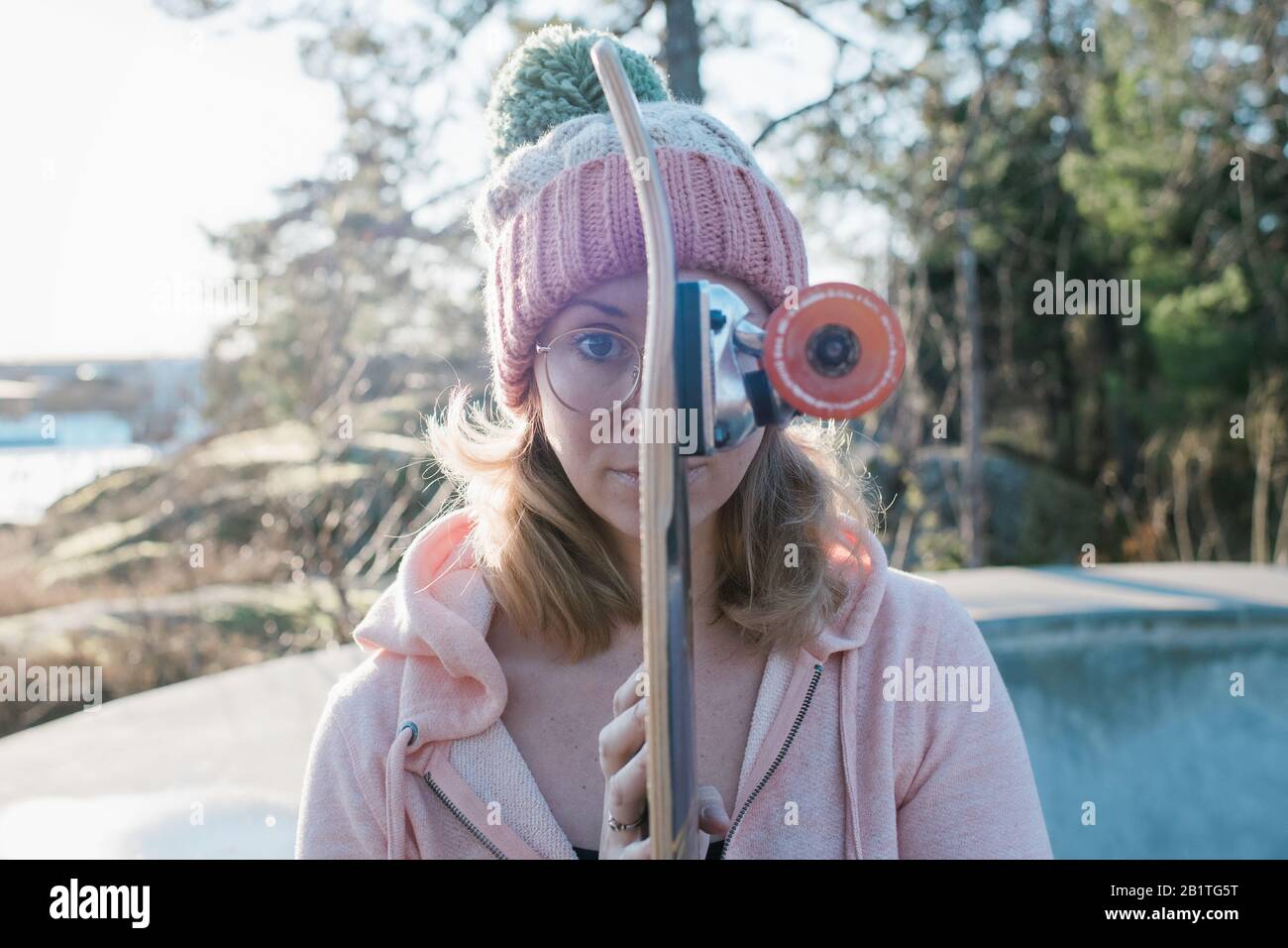 portrait d'une femme tenant son skateboard devant son visage Banque D'Images