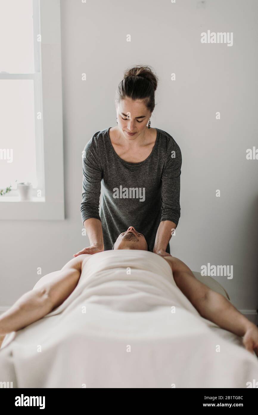 une massothérapeute féminine traite le patient masculin sur une table de massage Banque D'Images