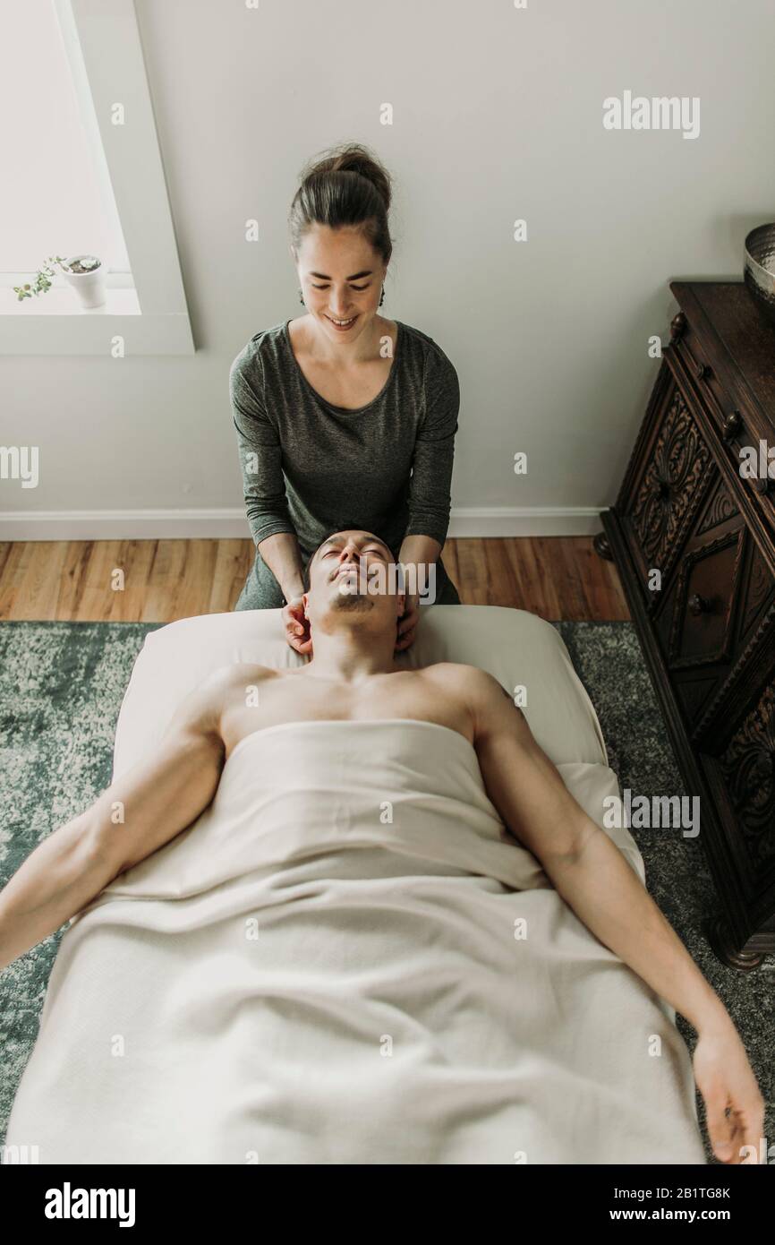 le massothérapeute souriant traite le cou du patient masculin Banque D'Images