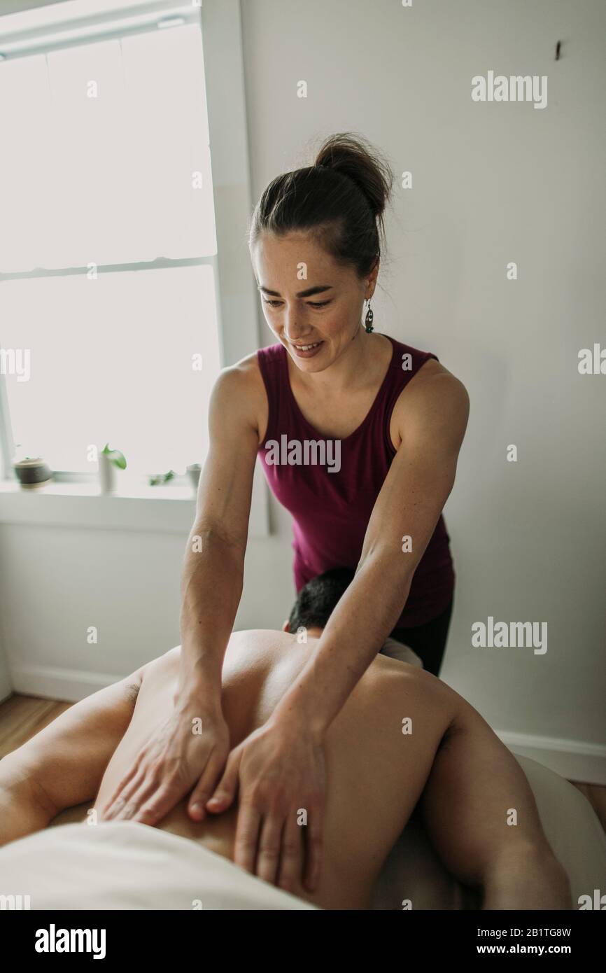 Une massothérapeute femme travaille sur le dos de sa patiente masculine. Banque D'Images