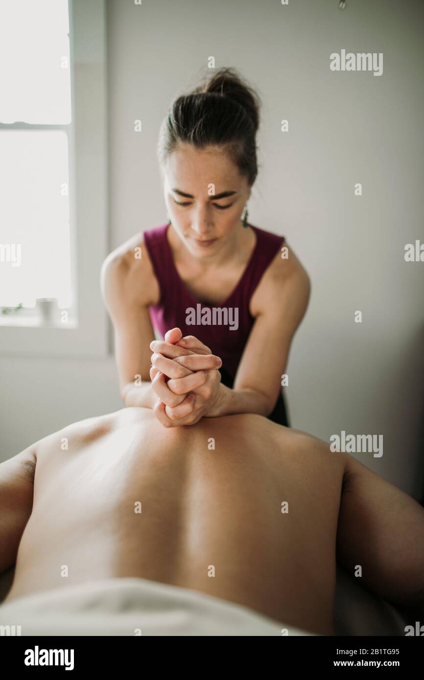 La massothérapeute féminine utilise les avant-bras pour travailler sur le dos du patient mâle Banque D'Images