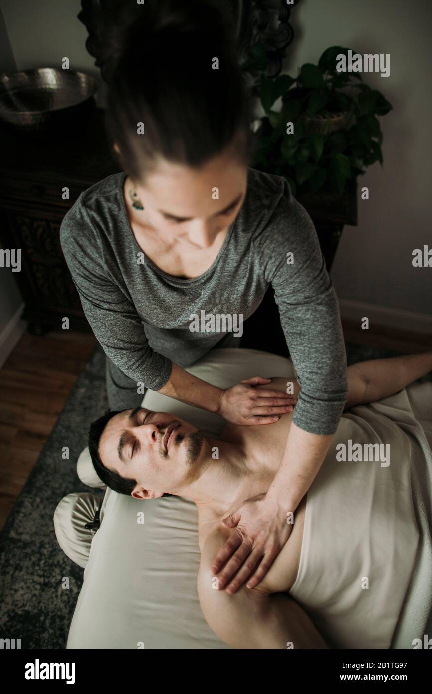 Le client de massage masculin reçoit une pression sur ses épaules de la part du thérapeute Banque D'Images