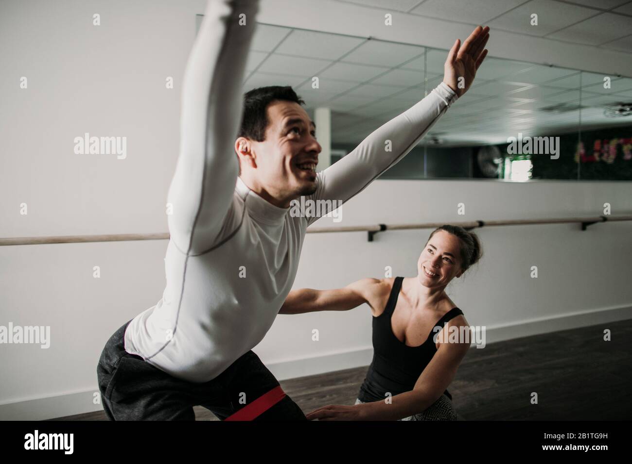 le masculin fait des squats comme son entraîneur personnel féminin regarde et coache Banque D'Images