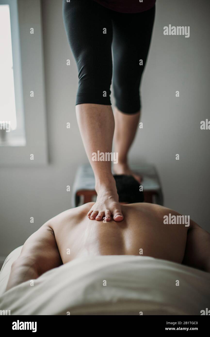 le massothérapeute utilise la technique de l'ashiatsu pour travailler sur le dos du patient Banque D'Images