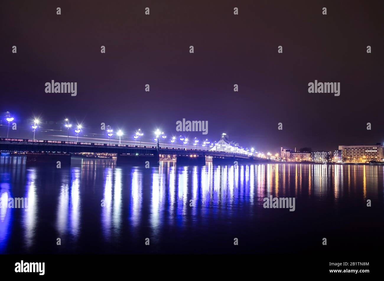 Vue sur le pont de pierre à Riga la nuit, Lettonie. Pont en pierre de Riga le soir. Route éclairée et bâtiment de la bibliothèque nationale. Banque D'Images