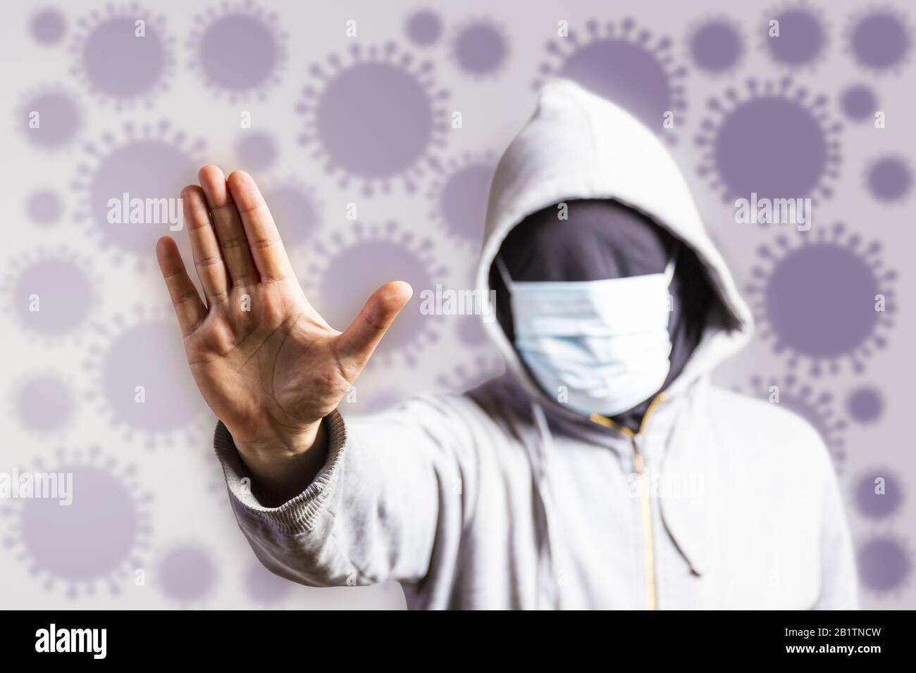 Homme non reconnaissable Avec sweat à capuche, portant un masque et montrant le geste d'arrêt de la main contre l'arrière-plan flou de virus - concept de santé - Stop corona virus Banque D'Images