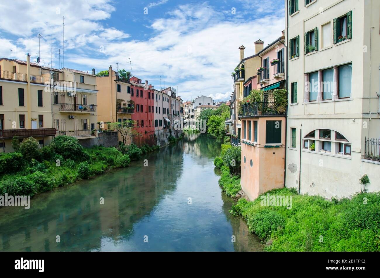 Rue traditionnelle du canal avec des bâtiments colorés, des buissons verts et le ciel bleu à Padoue, en Italie. Paysage urbain italien animé Banque D'Images