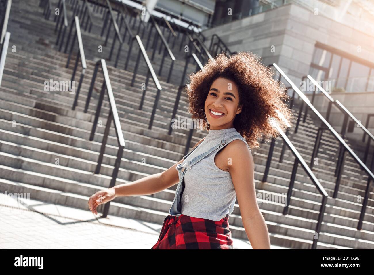 Jeune femme africaine américaine dans la rue de la ville debout sur les escaliers souriant gai Banque D'Images