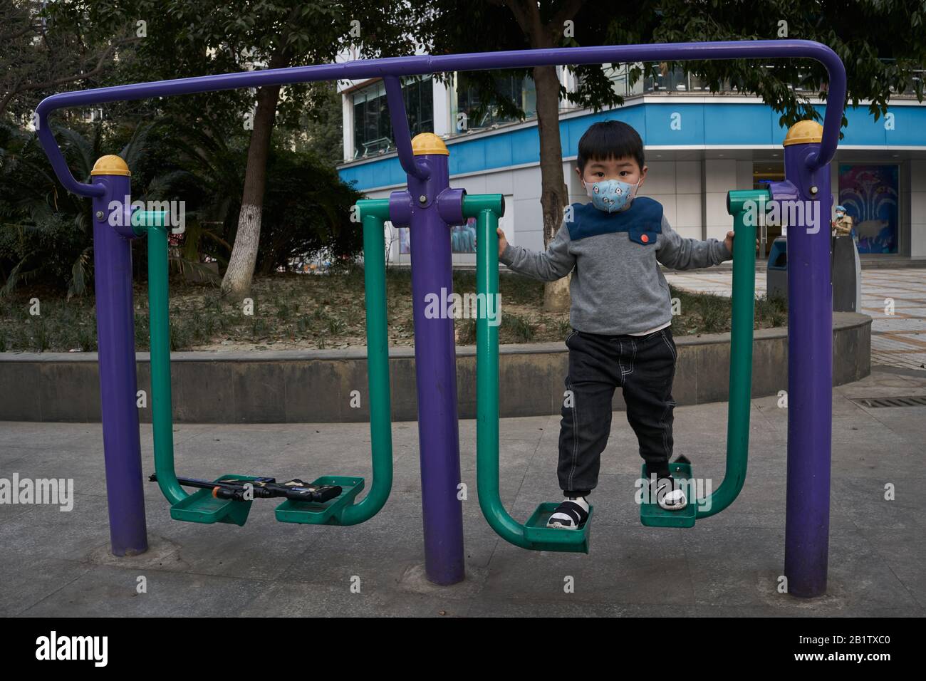 Un enfant qui utilise le marcheur dans un parc de loisirs portant un masque chirurgical pour prévenir la maladie du coronavirus en cours. Banque D'Images