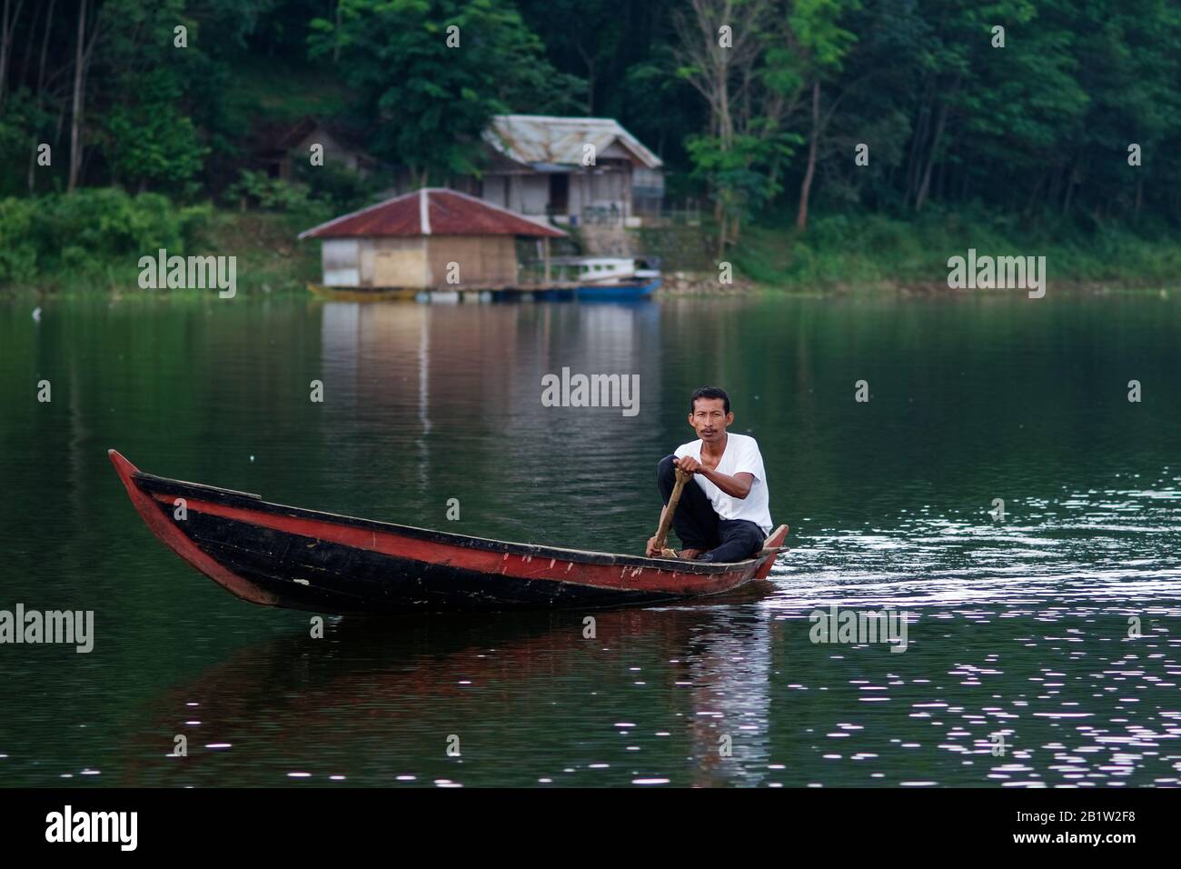 Homme aviron sur une barque sur le lac de Cianjur - Java, Indonésie. Cianjur est une ville agréable à une journée de bus de Jakarta. Il est célèbre pour la culture du riz. a lac avec Banque D'Images