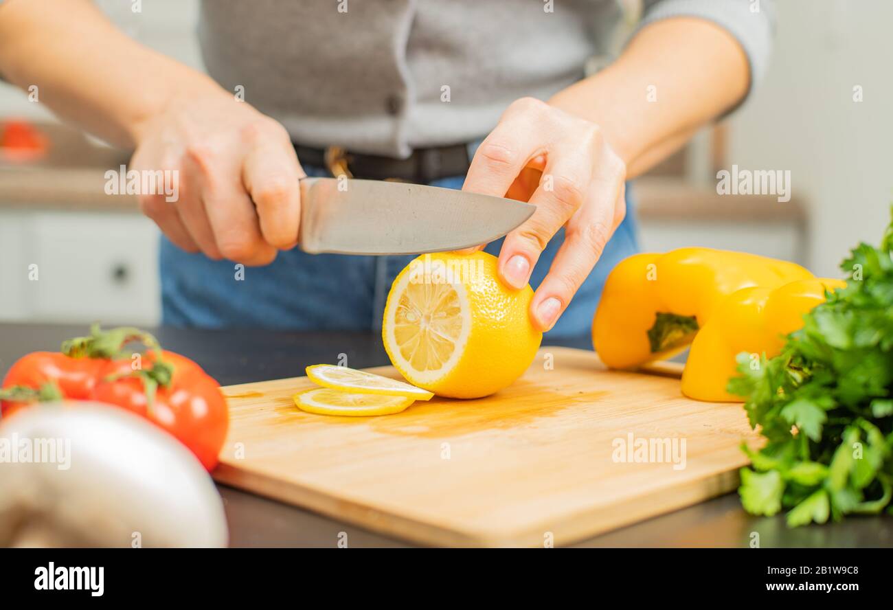Citron frais. La femme coupe le citron sur la table de cuisine. Banque D'Images