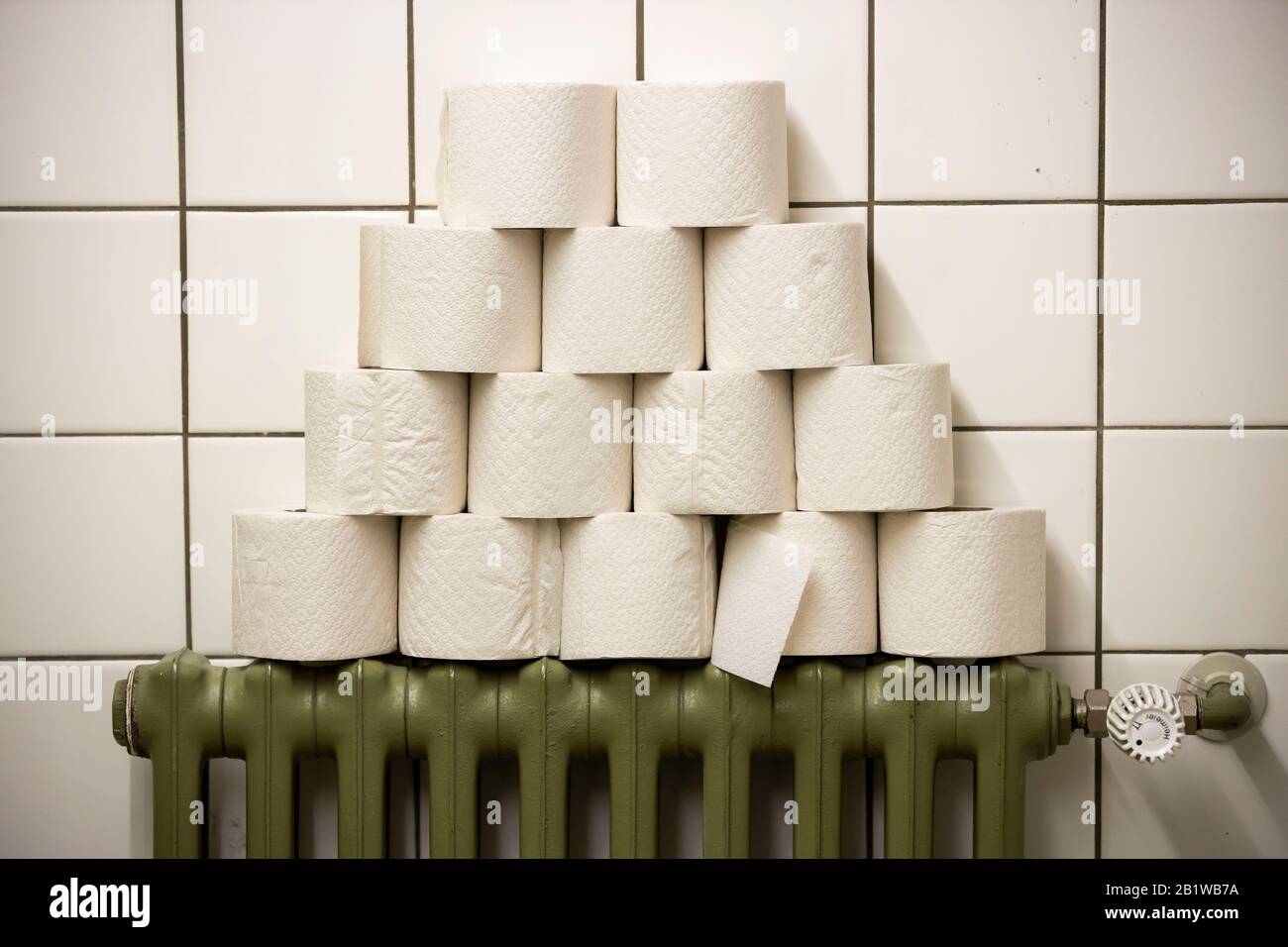 Rouleaux de papier toilette empilés sur un radiateur, dans des toilettes publiques Banque D'Images