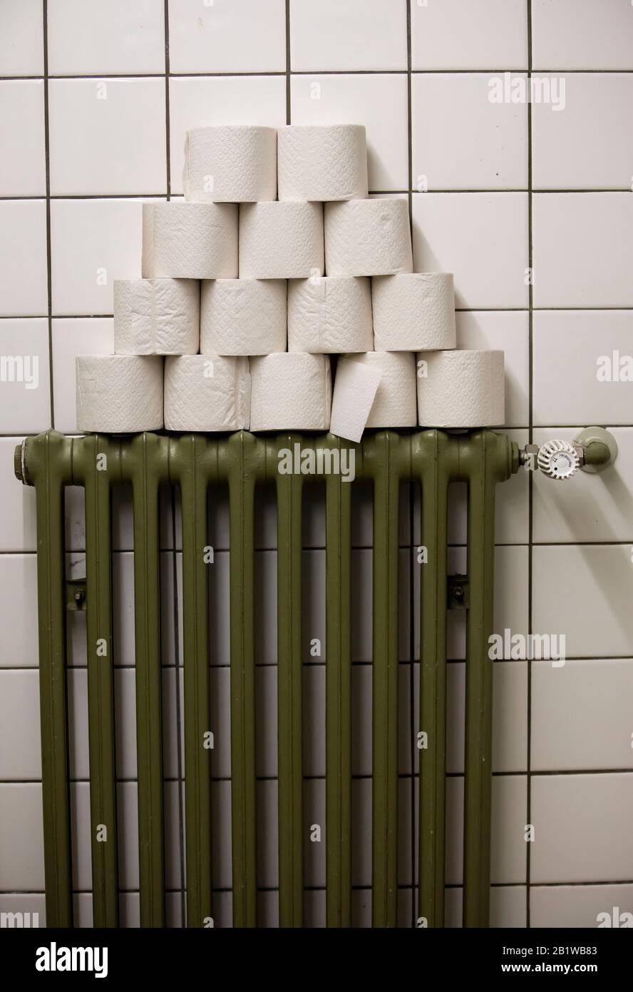 Rouleaux de papier toilette empilés sur un radiateur, dans des toilettes publiques Banque D'Images