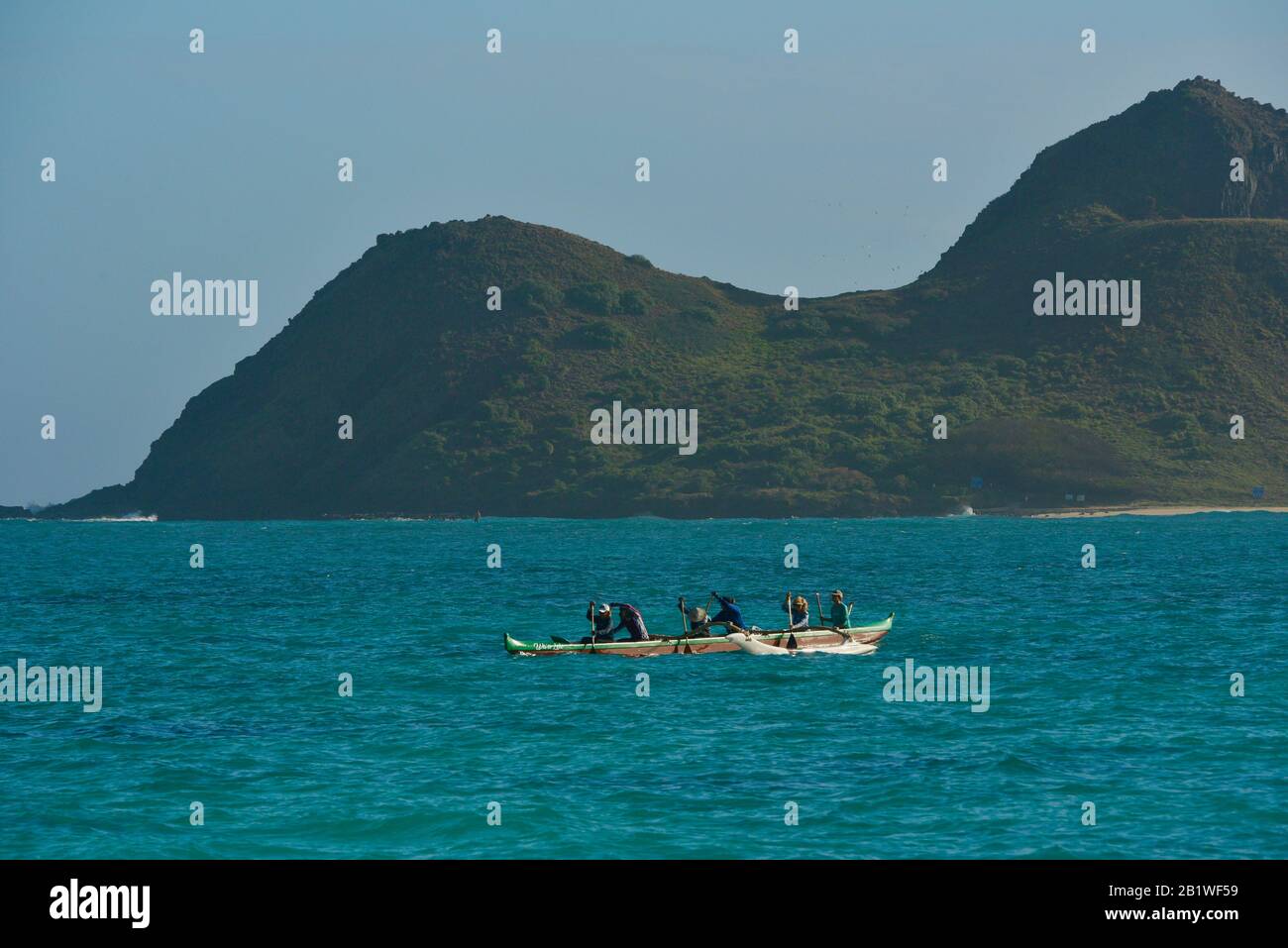 Les gens pagayant en canoë à l'outrigger dans les eaux turquoise au large de Lanikai Beach, Moku Nui île derrière (partie des îles Mokulua), Oahu, Kailua, Hawaï, États-Unis Banque D'Images