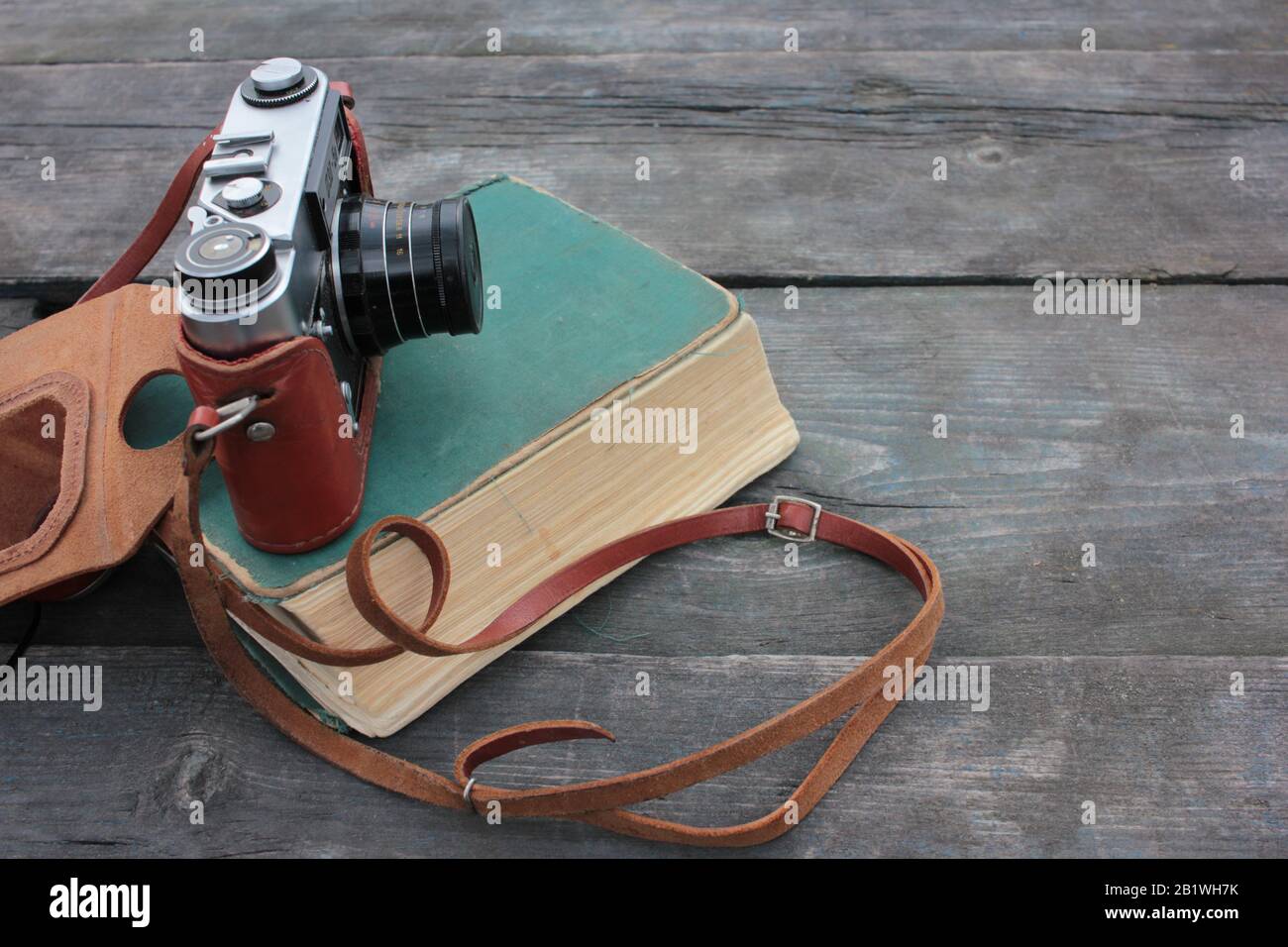 Ancien appareil photo ancien et livre de shabby sur une table en bois rugueuse, à l'extérieur. Vue de dessus, espace de copie Banque D'Images