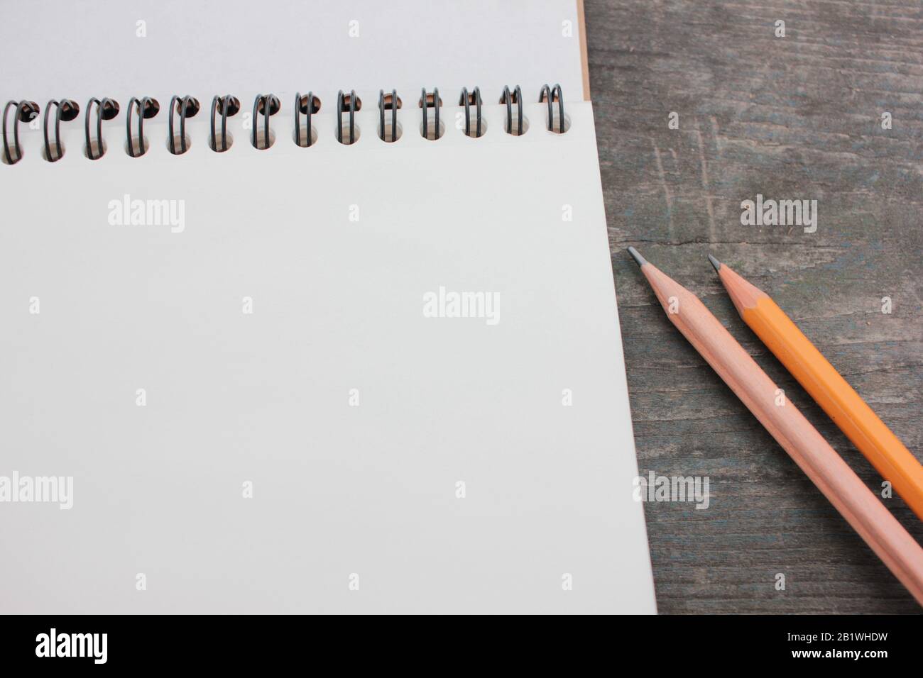 Ouvrir le croquis sur une spirale avec des pages blanches et un crayon sur une table en bois sombre rugueuse. Vue de dessus, espace de copie Banque D'Images