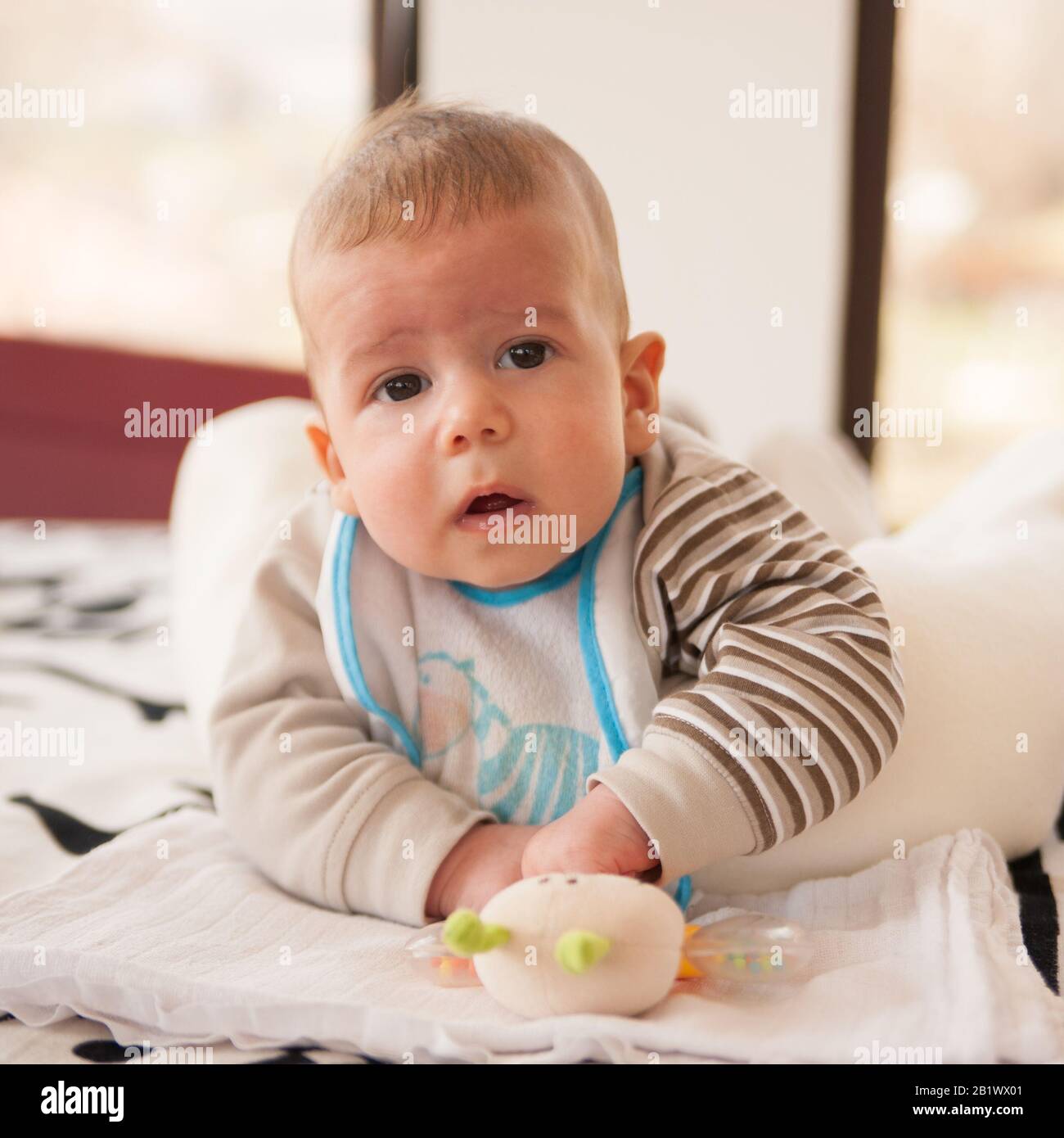 un bébé de 3 mois joue avec ses jouets et regarde l'appareil photo Banque D'Images