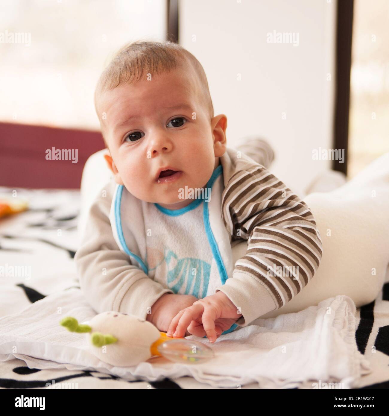 un bébé de 3 mois joue avec ses jouets et regarde l'appareil photo Banque D'Images