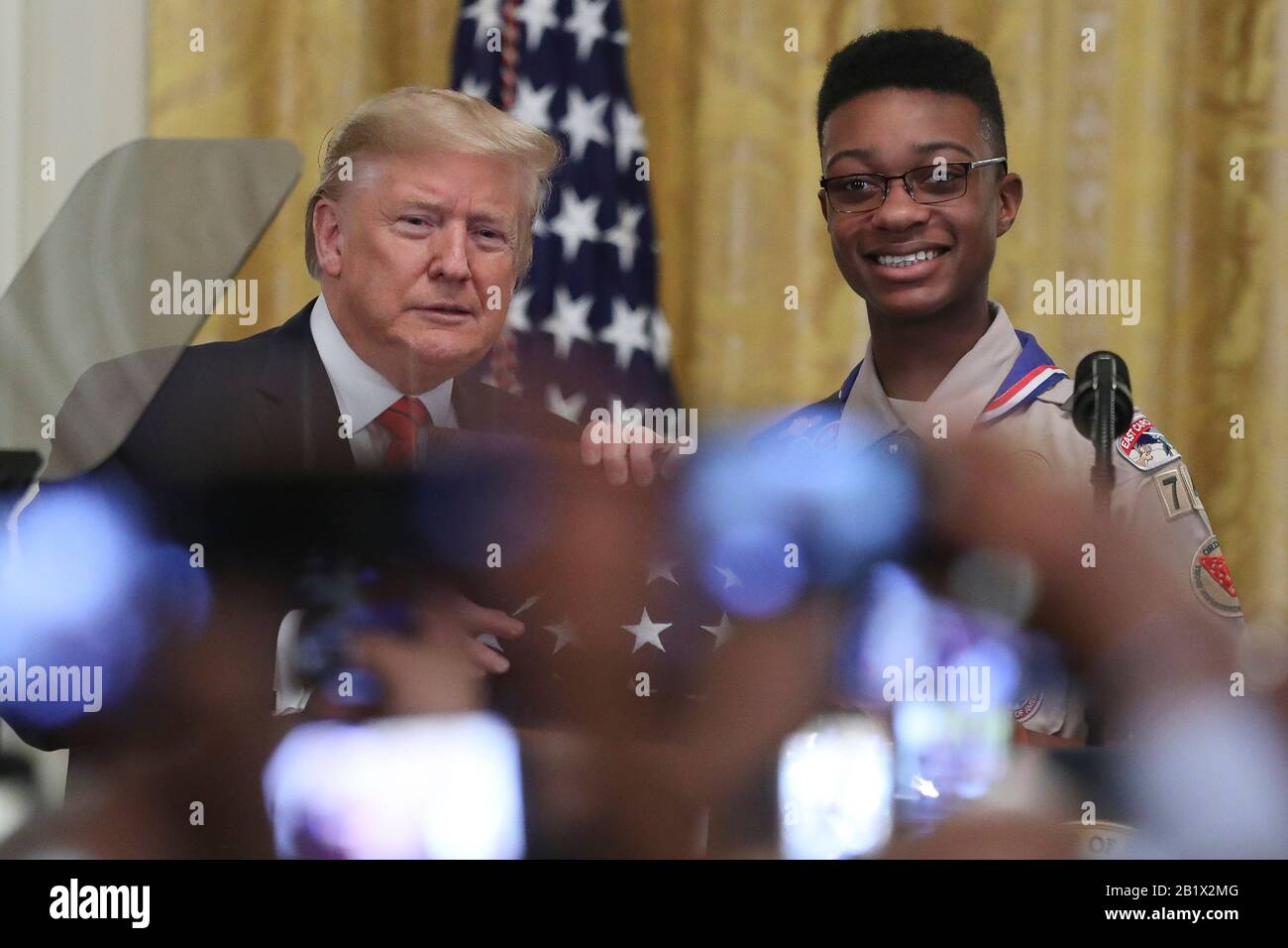 Washington, États-Unis. 27 février 2020. Le président Donald Trump présente un drapeau qui s'est envolé à bord de Marine One à Eagle Scout Alphonso Hill Jr., lors d'une réception du mois de l'histoire de l'Afrique américaine dans la salle est de la Maison Blanche à Washington, DC, le 27 février 2020. (Photo d'Oliver Contreras/SIPA USA) crédit: SIPA USA/Alay Live News Banque D'Images