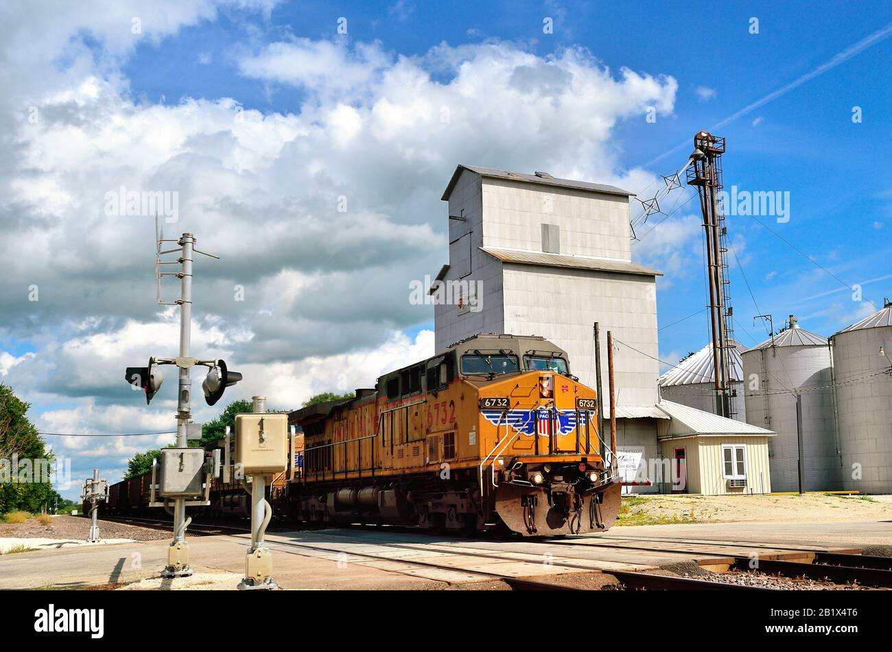 Creston, Illinois, États-Unis. Un train à charbon vide Union Pacific, dirigé par trois locomotives passant par un élévateur de grain et un passage à niveau. Banque D'Images