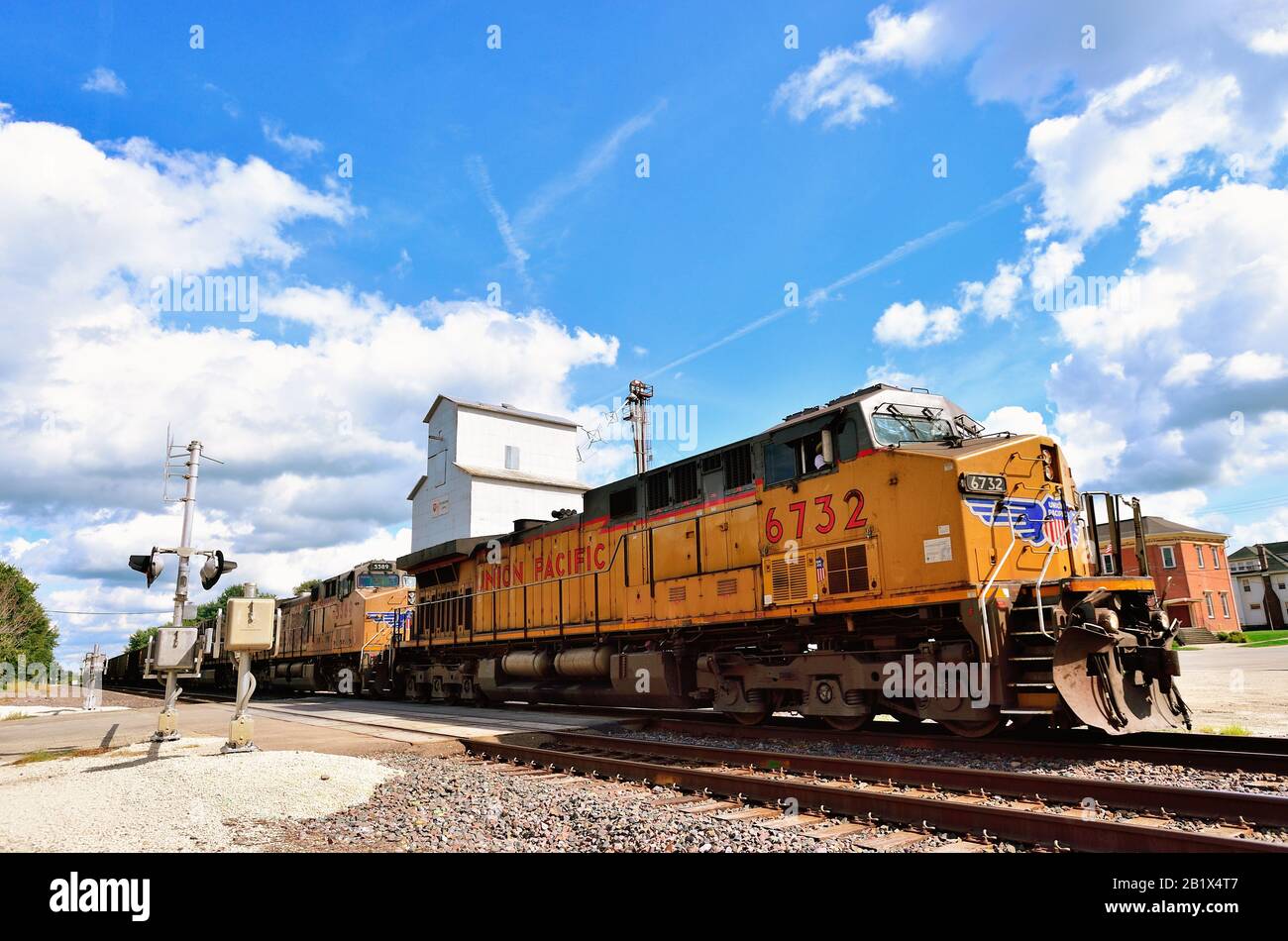 Creston, Illinois, États-Unis. Un train à charbon vide Union Pacific, dirigé par trois locomotives passant par un élévateur de grain et un passage à niveau. Banque D'Images