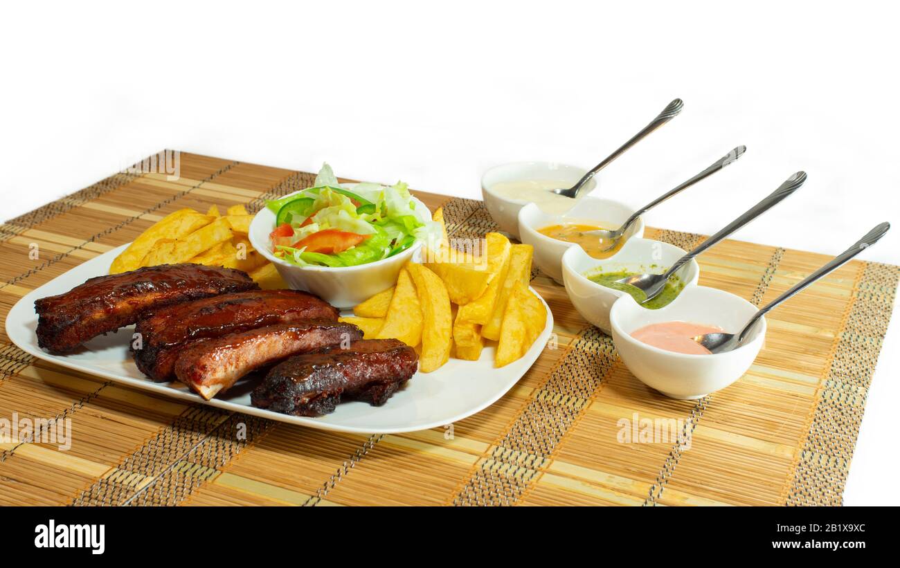 Plaque de côtes de barbecue accompagnée de frites et de salade de tomates et de laitue sur fond blanc Banque D'Images