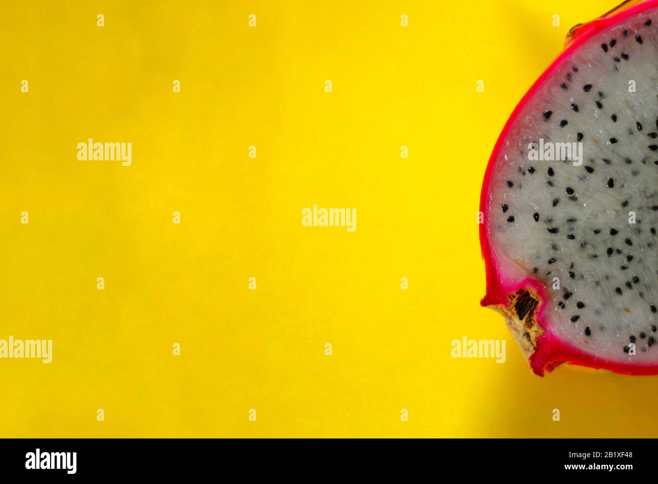 Décor tropical minimaliste thème d'été d'un fruit de dragon tranché sur un fond jaune Banque D'Images