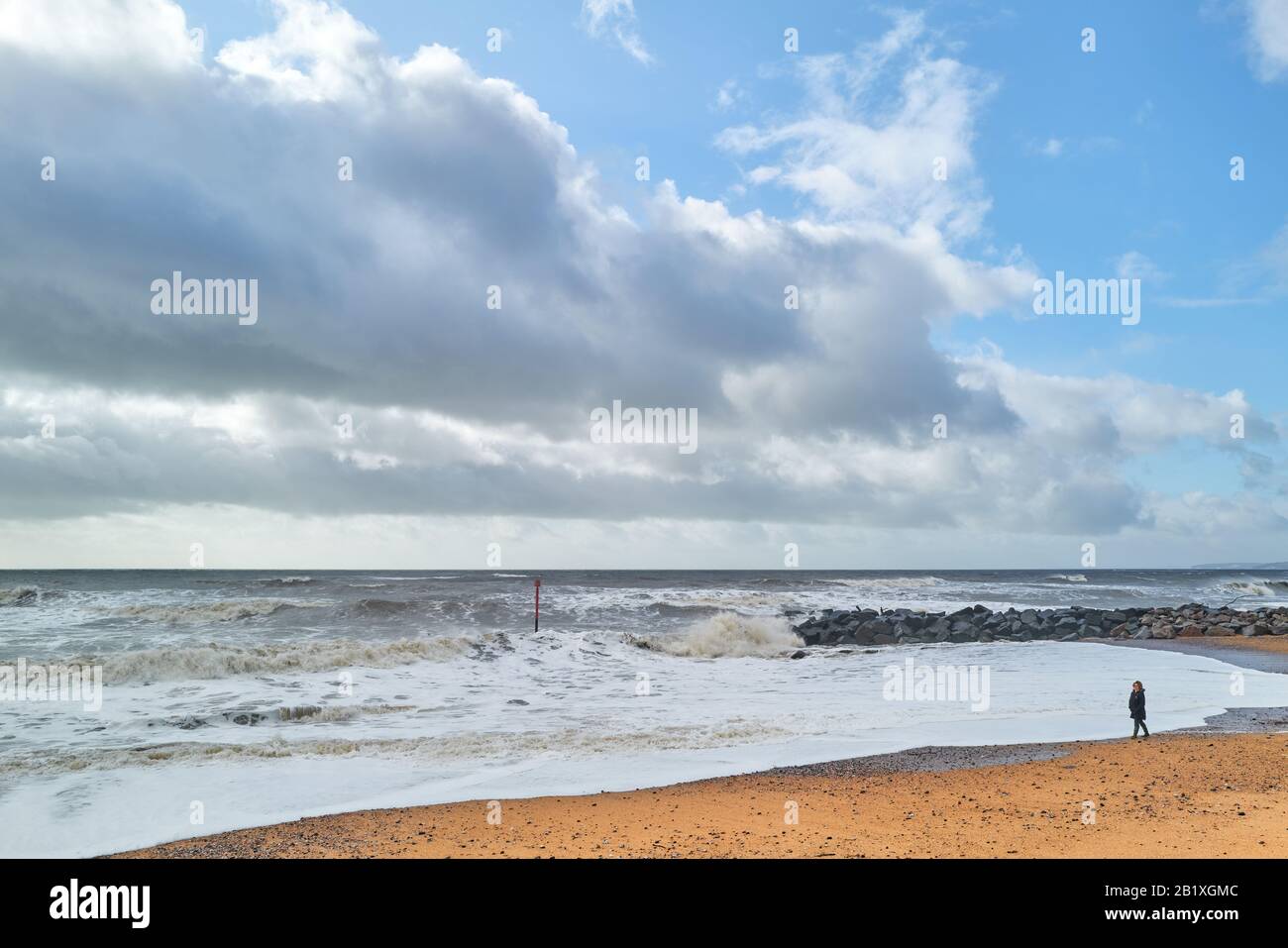 Une seule personne se tient sur la rive pendant les temps d'hiver pluviaux, la ligne côtière du patrimoine jurassique, la mer de la Manche à West Bay, Dorset, Angleterre. Banque D'Images