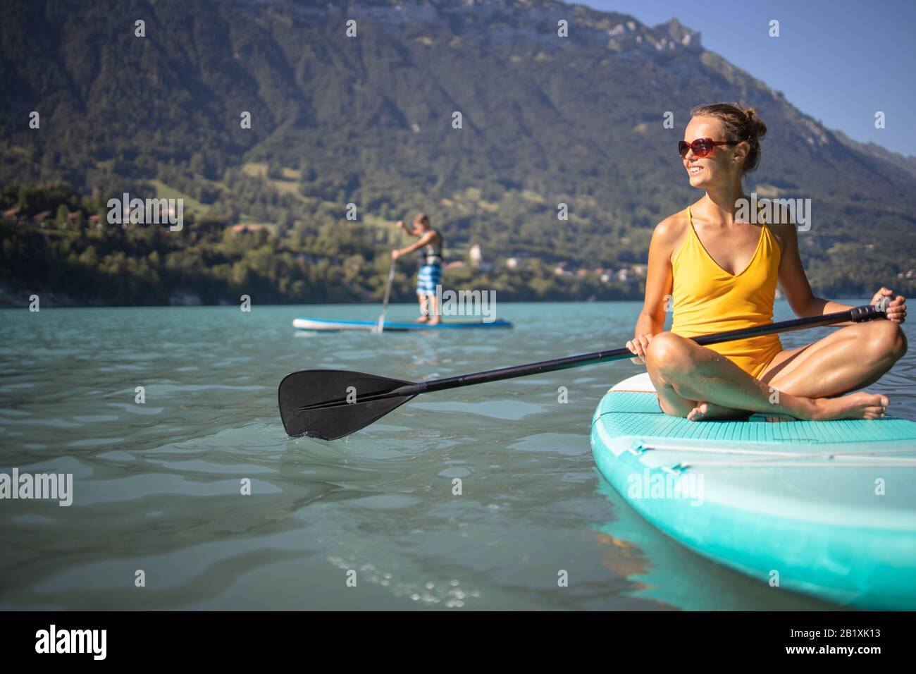 SUP Stand Up Paddle board concept - jolie jeune femme paddle sur un beau lac en fin d'après-midi chaud - léger coup de underwater Banque D'Images