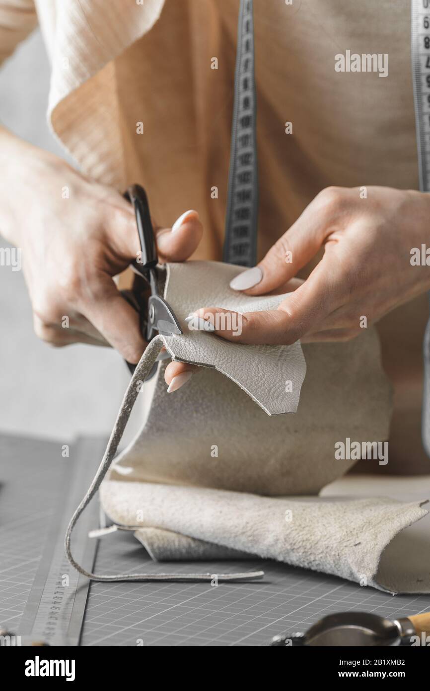 Femme concepteur de sac à main mesurant le cuir et découpant les détails dans un atelier studio Banque D'Images