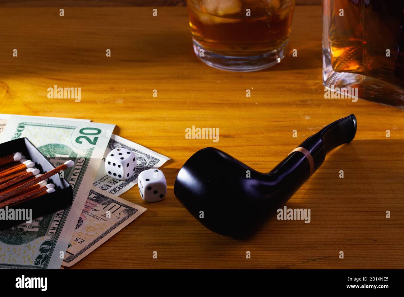 Jeux de hasard - tuyau de tabac, dés blancs, whisky écossais et billets de dollars sur la table en bois Banque D'Images