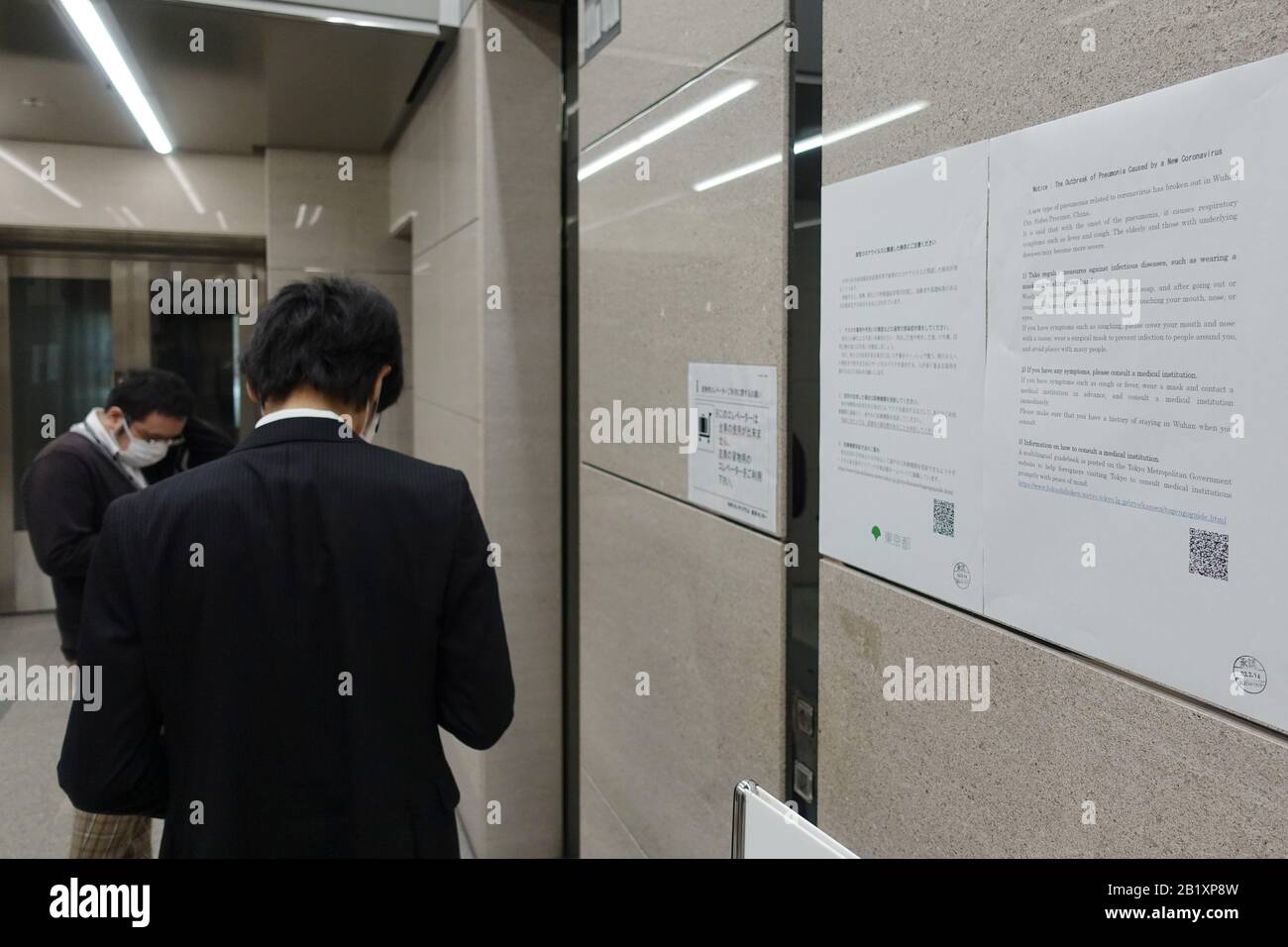 Tokyo, Japon. 27 février 2020. Les gens attendent un ascenseur à côté d'un avis de coronavirus dans un immeuble de bureaux à Tokyo, Japon, 27 février 2020. Vendredi, le ministre japonais de l'éducation, Koichi Hagiuda, a demandé à tous les élèves de rester à l'intérieur et de ne pas fréquenter les écoles fermées pour contenir la COVID-19. Crédit: Du Xiaoyi/Xinhua/Alay Live News Banque D'Images