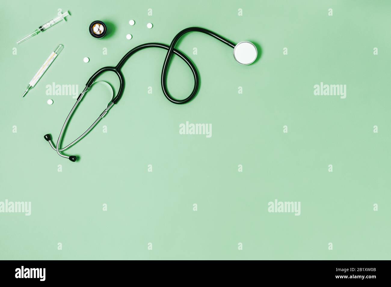 Fond vert médical avec stéthoscope, thermomètre, seringue et comprimés. Banque D'Images