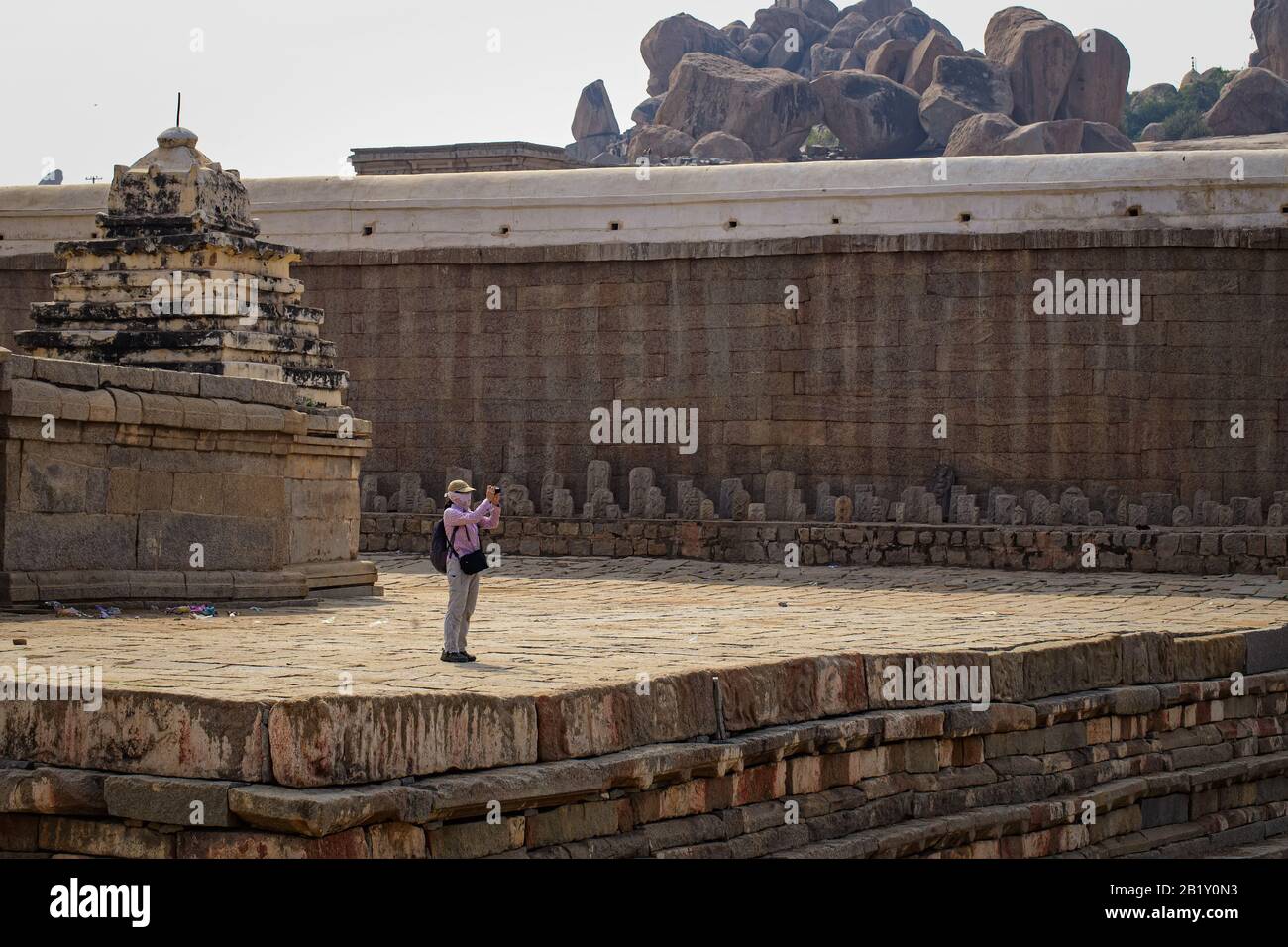 Un touriste se tient sur le rivage d'un lac de temple et photographie près du temple de Virupaksha. Hampi, Karnataka Banque D'Images