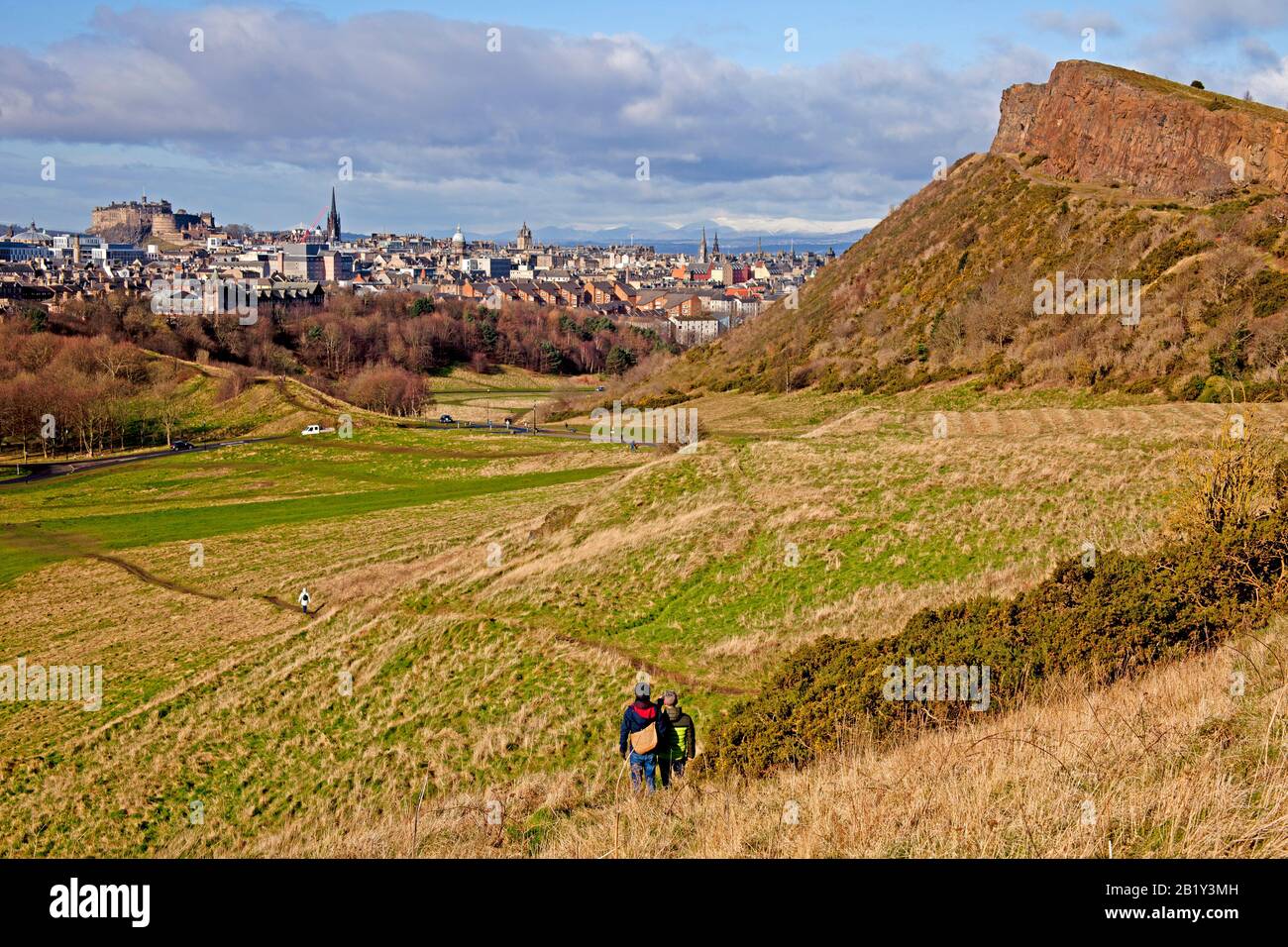 Holyrood Park, les touristes marchant avec une vue vers Salisbury Crags et la ville d'Edimbourg en arrière-plan, Ecosse, Royaume-Uni Banque D'Images