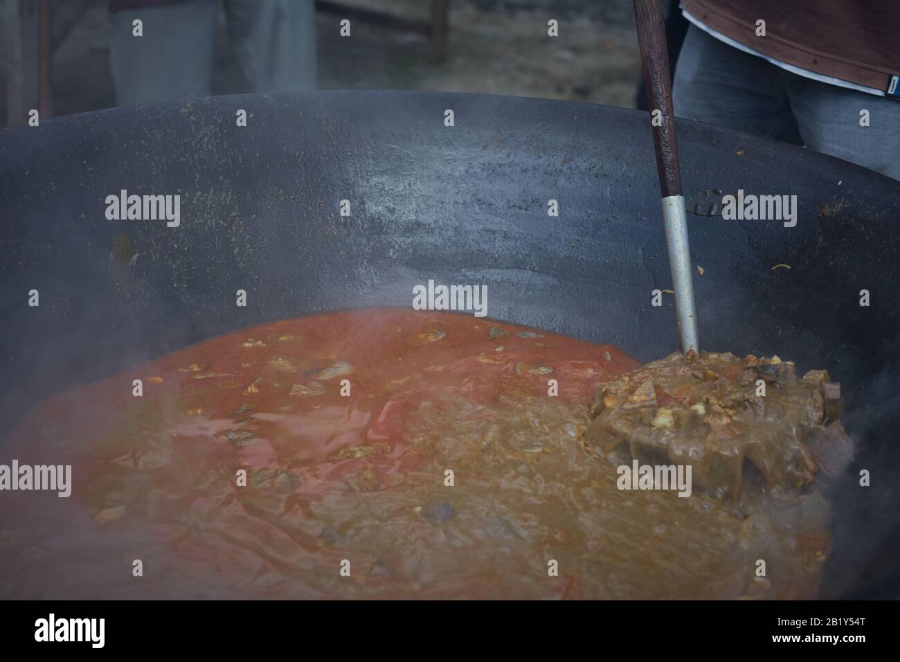 Cuisson de la viande traditionnelle Curry dans une grande poêle sur un feu de bois sur le marché indonésien de la nourriture de rue Banque D'Images