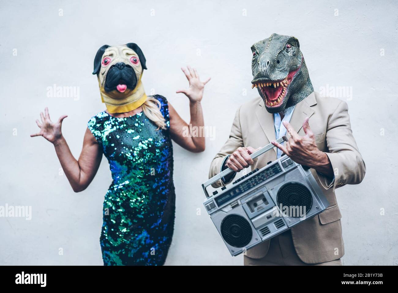 Un couple de seniors fou dansant pour une fête portant le t-rex et le masque de poulet - des gens à la mode âgés qui écoutent de la musique avec une chaîne stéréo boombox - Absurd et f Banque D'Images