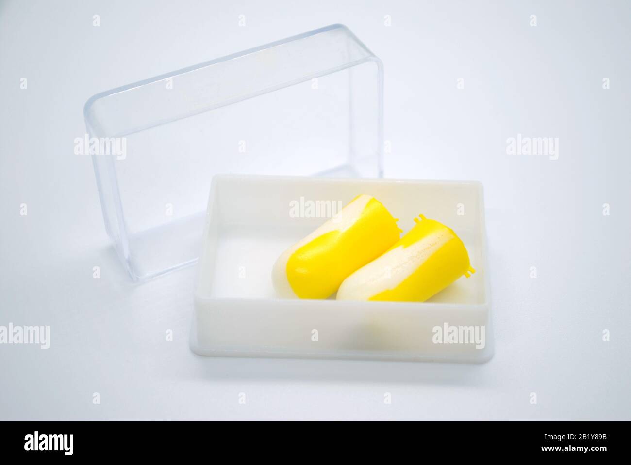 Bouchons d'oreille isolés colorés en blanc et jaune à l'intérieur d'une boîte en plastique blanc avec couvercle transparent Banque D'Images
