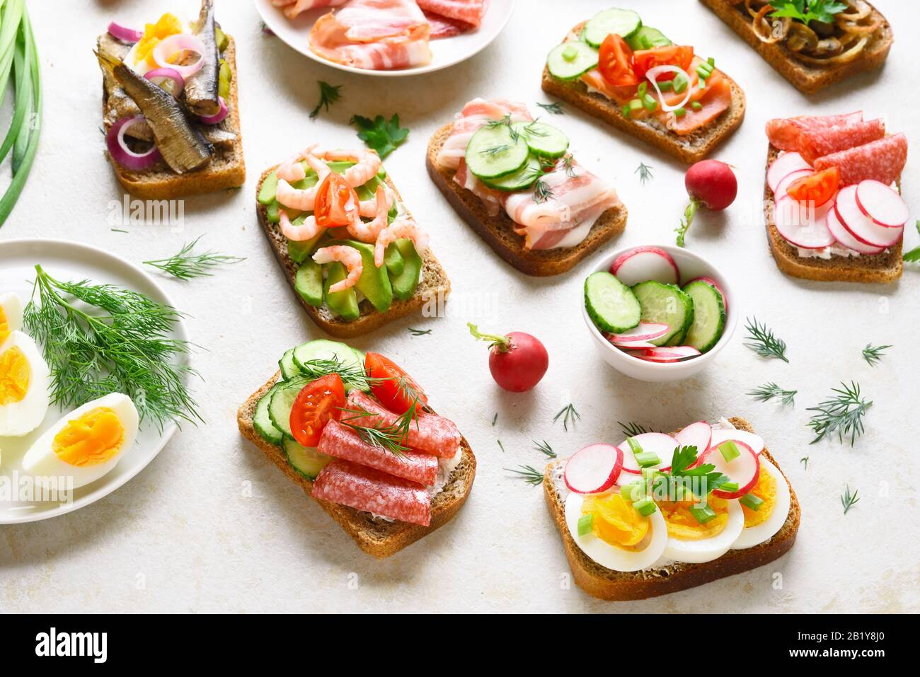 Assortiment de sandwichs ouverts sur fond de pierre légère. Différents sandwichs avec viande, légumes, fruits de mer. En-cas savoureux et sains. Banque D'Images