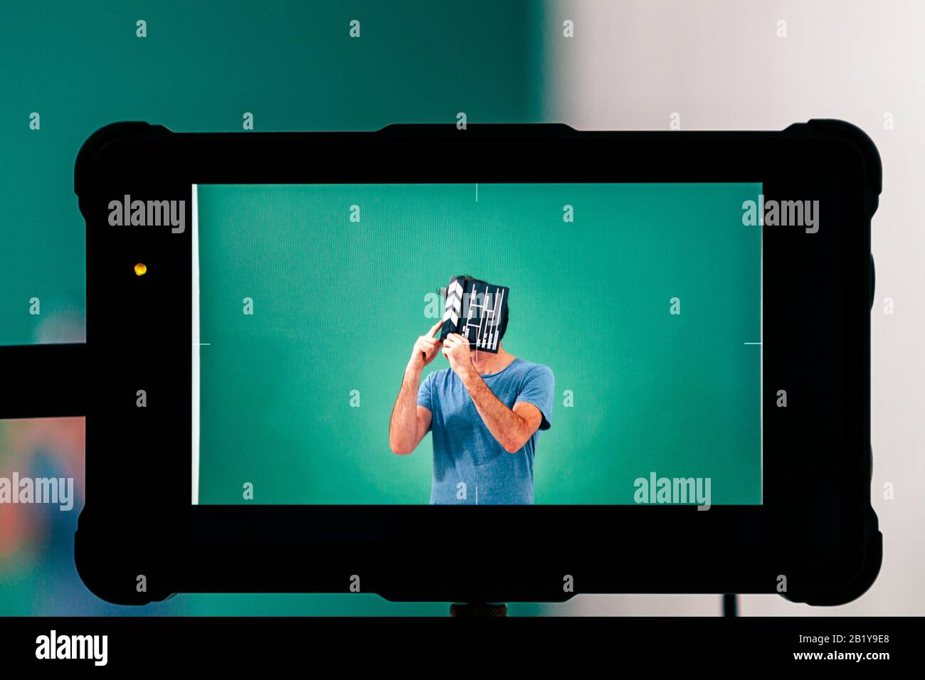 vue de l'écran de la caméra vidéo d'un homme en studio tenant un clapperboard donnant l'action Banque D'Images