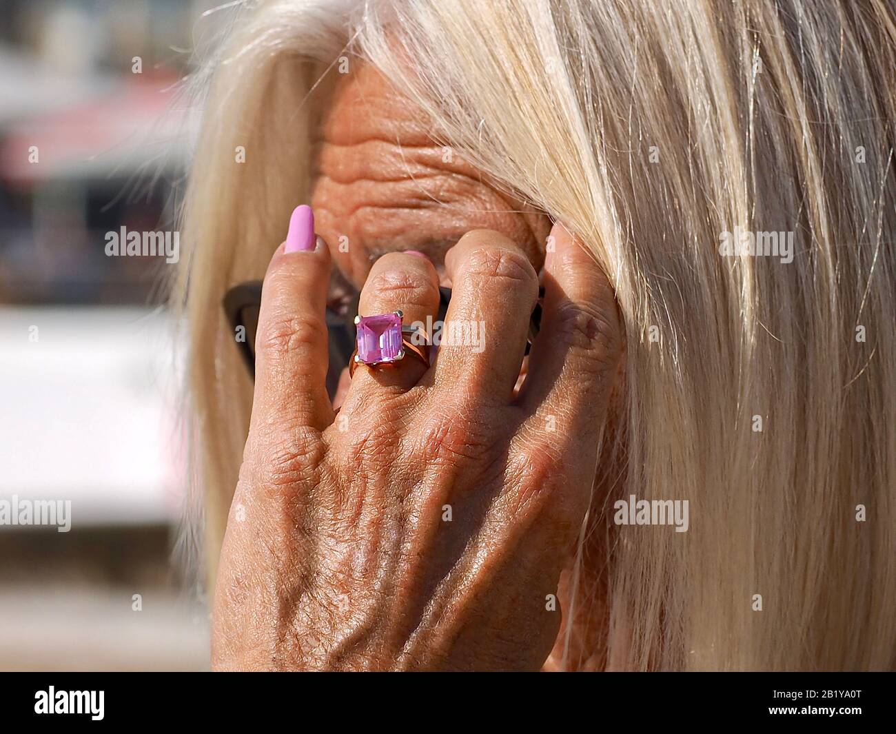 Femme avec des cheveux blonds tient sa main devant un visage Banque D'Images