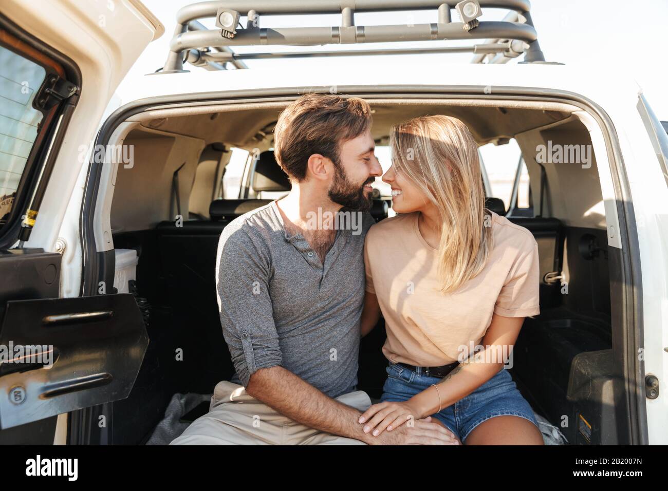 Image d'un heureux heureux heureux jeune couple aimant extraordinaire plein air ensergeant en voiture à la plage. Banque D'Images