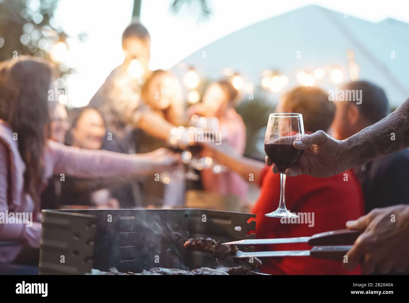 Bonne famille faisant des toasts de fête à la fête du barbecue - les jeunes et les parents plus âgés ayant un dîner amusant ensemble dans le jardin Banque D'Images
