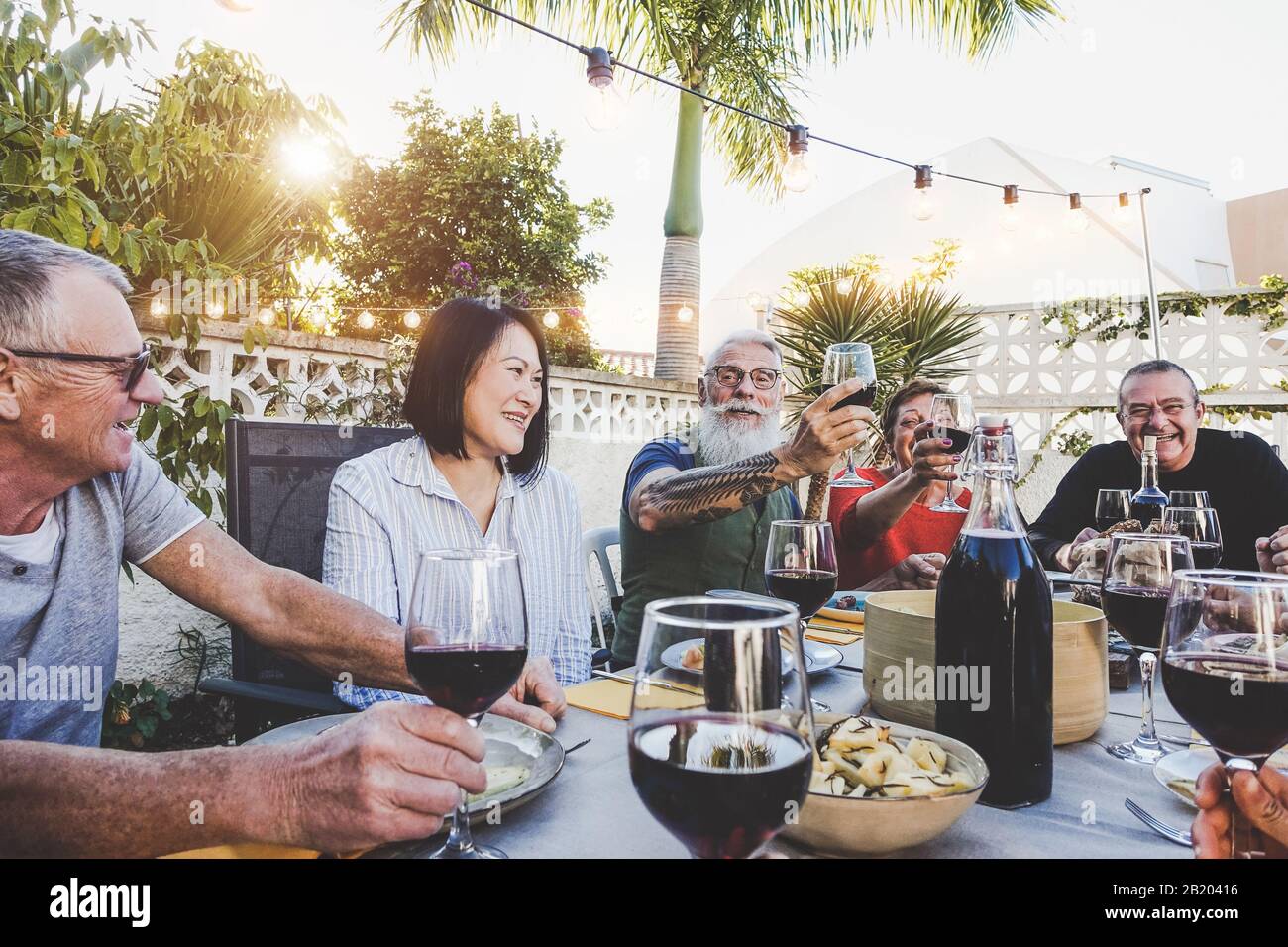 Bonne famille manger et boire du vin rouge au dîner barbecue en plein air - des amis fatigués se dégustant ensemble au restaurant Banque D'Images
