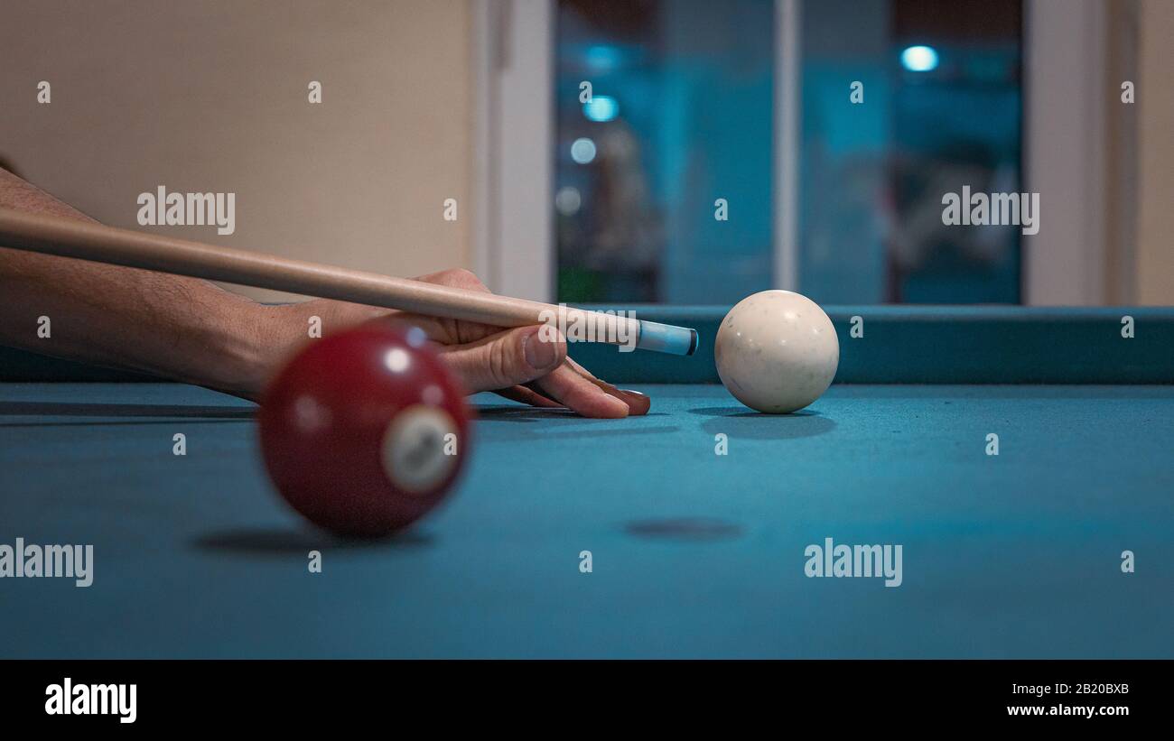 Main d'un homme jouant au billard. La boule blanche domine l'image Banque D'Images