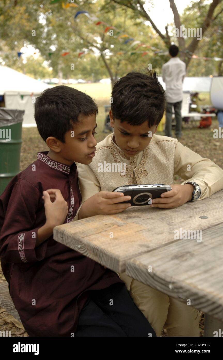 Austin, Texas 12 novembre 2005 : les garçons jouent avec un appareil de jeu portable Sony PSP à la fin du festival du Ramadan (Eid) pour la communauté musulmane du Texas central. L'événement présente la nourriture, la danse et les festivités du monde musulman. ©Bob Daemmrich Banque D'Images