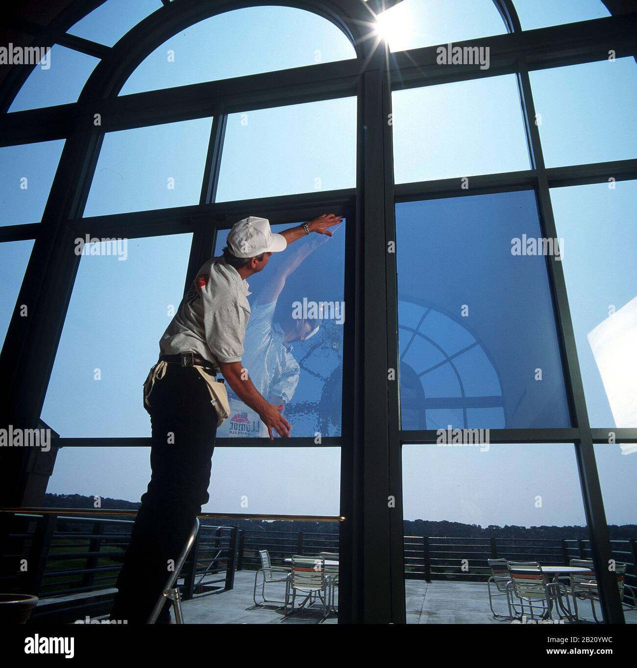 Austin, Texas : technicien installant un film spécialisé pour colorer les fenêtres personnalisées à l'intérieur du club privé de country club pour améliorer l'efficacité énergétique à l'intérieur du bâtiment. ©Bob Daemmrich Banque D'Images