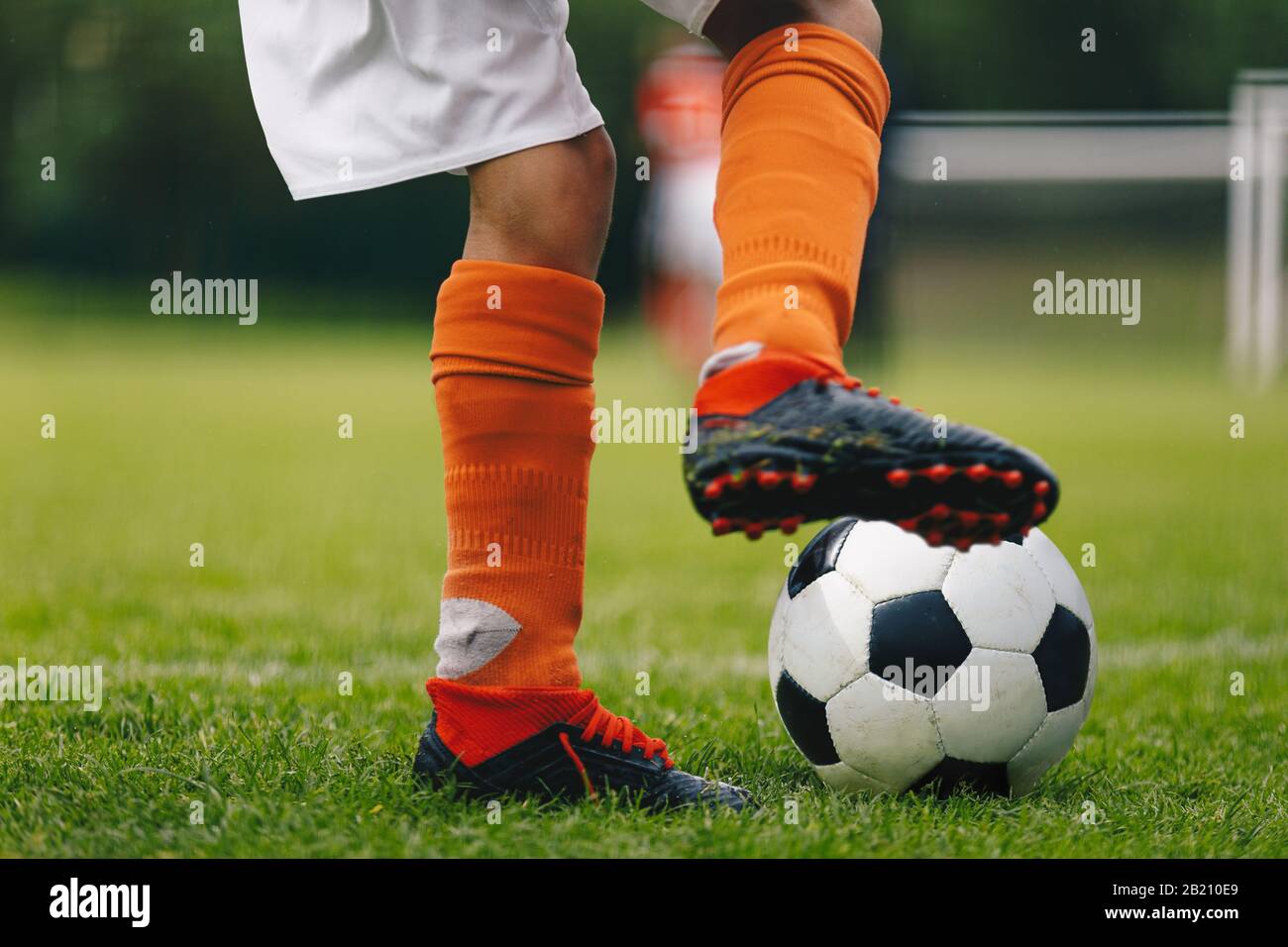 Coup de ballon de football. Gros plan sur les jambes et les pieds du joueur  de football dans les chaussettes rouges et les crampons courir et dribbler  avec le ballon. Joueur de